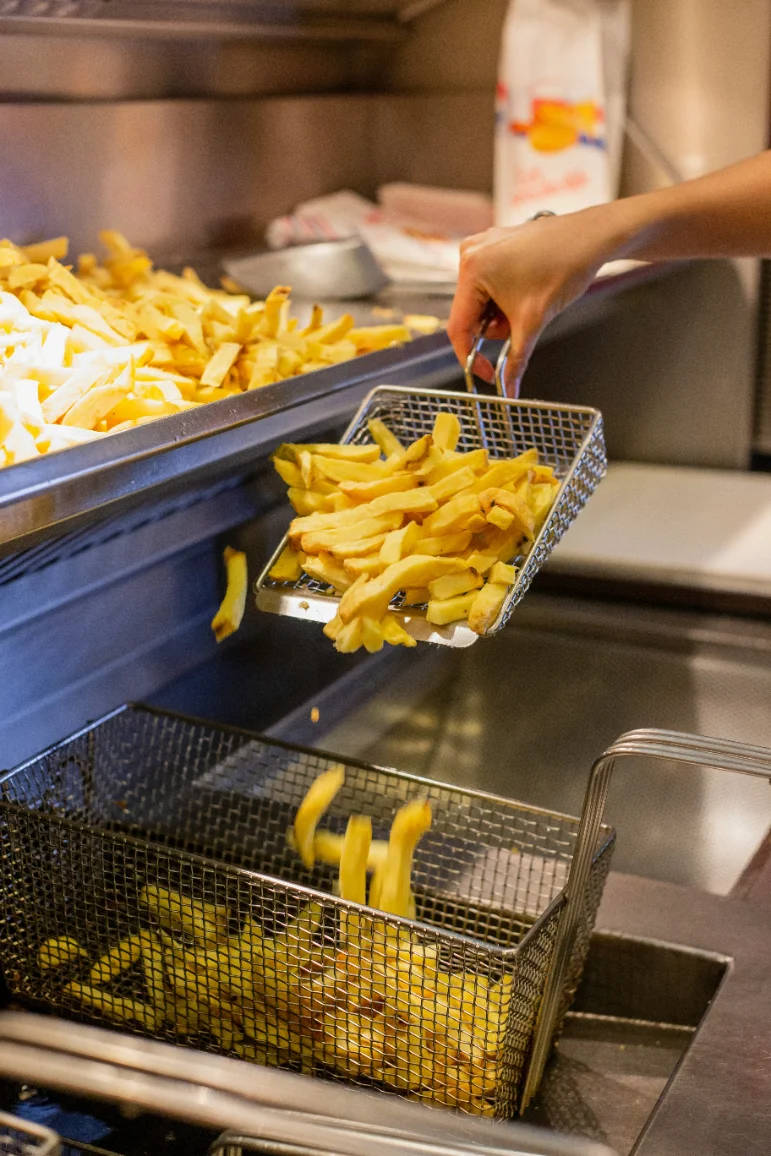 Vers gebakken friet wordt uit de friteuse geschept
